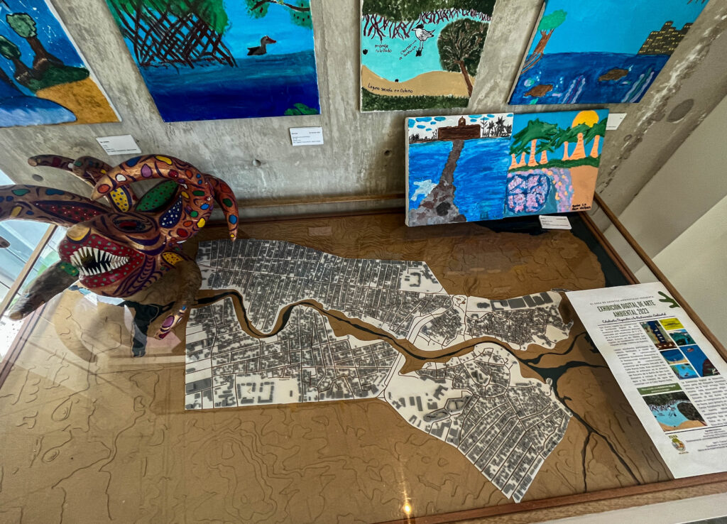 Map pieces sit on a table alongside a ceramic statue and several paintings.