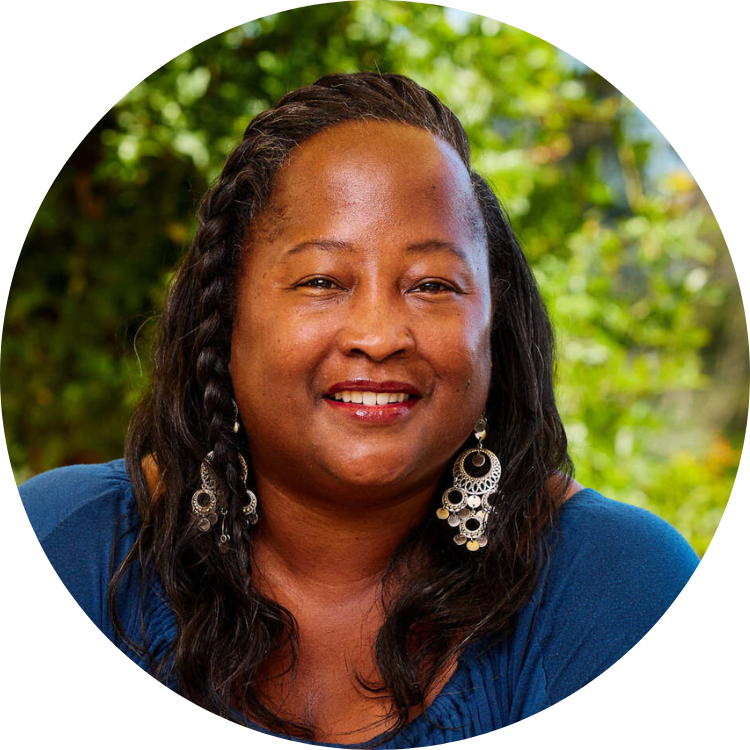 Picture of Tiffany Johnson. Tiffany appears in front of a nature background, wearing a deep blue top and silver earrings.