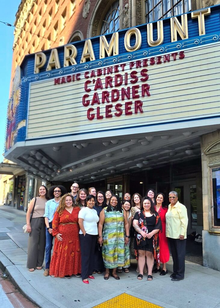 A group of people stand underneath a marquee that reads Magic Cabinet presents C'Ardiss Gardner Gleser